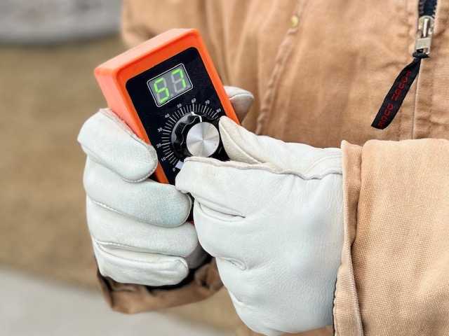 Two gloved hands holding a W.A.C. Welding remote control.